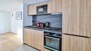 Eine moderne Küche mit Holzausstattung, einer schwarzen Arbeitsplatte, einer eingebauten Mikrowelle, einer Kaffeemaschine und einem Geschirrspüler.