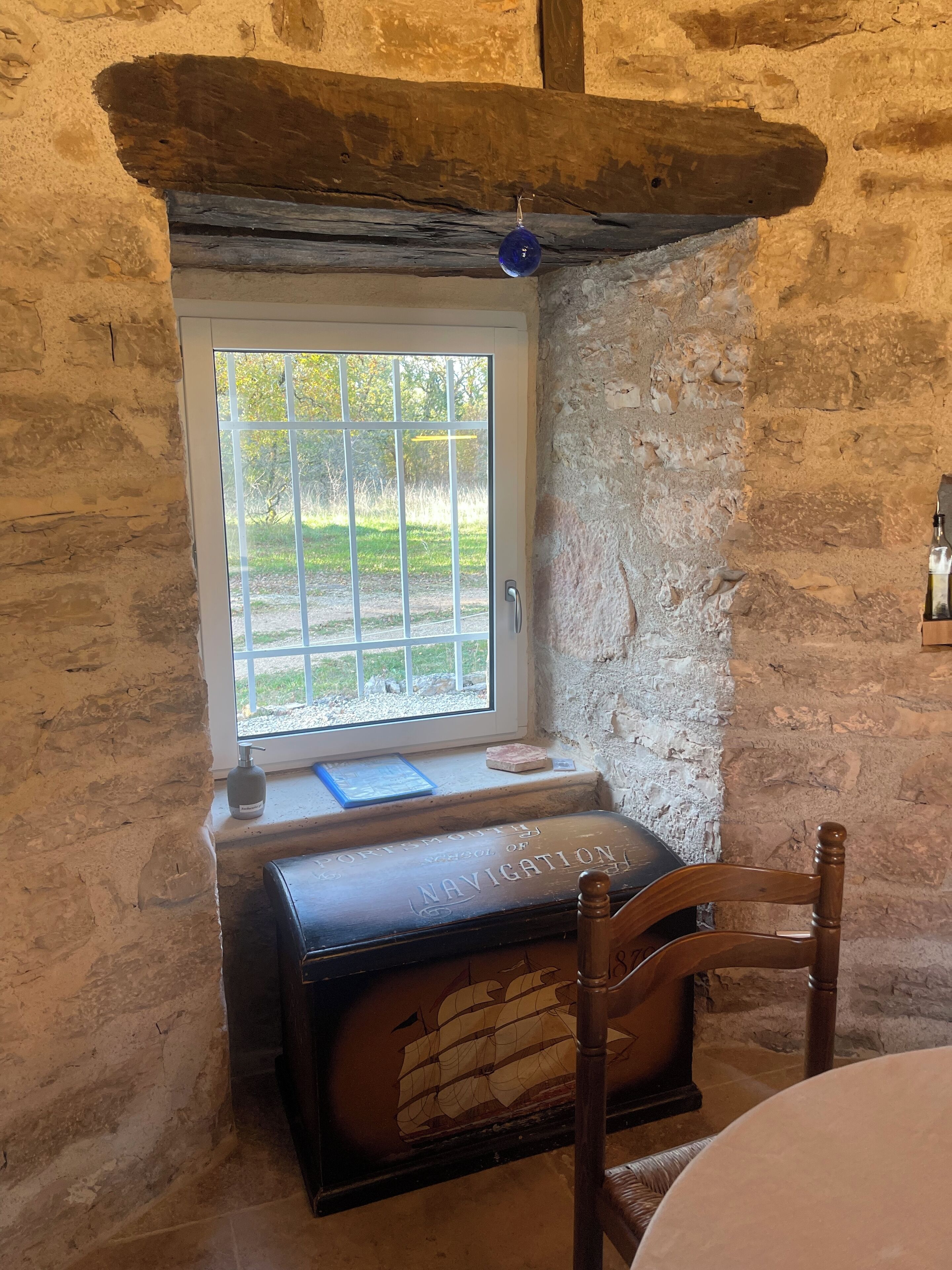 Une pièce rustique avec un banc en bois, une petite table et une fenêtre donnant sur un paysage verdoyant.
