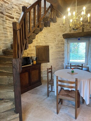 Cozy dining area with a table and chairs near a window, a wooden cabinet, and a chandelier.