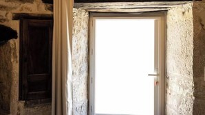 Ein Zimmer mit einer Steinswand, einer Holztür und einer Kandelaber.