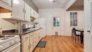A kitchen with white cabinets, a stove, and a dining area with a table and chairs.