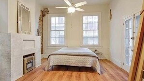 A bedroom with a bed, a ceiling fan, and a fireplace.