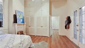 A bedroom with a bed, a wardrobe, a fireplace, and a door leading to another room.