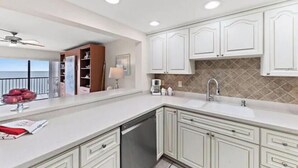 A modern kitchen with white cabinetry, a built-in oven, and a large island with a sink. - OCEANFRONT condo directly overlooking the clear blue water of the Gulf of Mexico (Madeira Beach)
