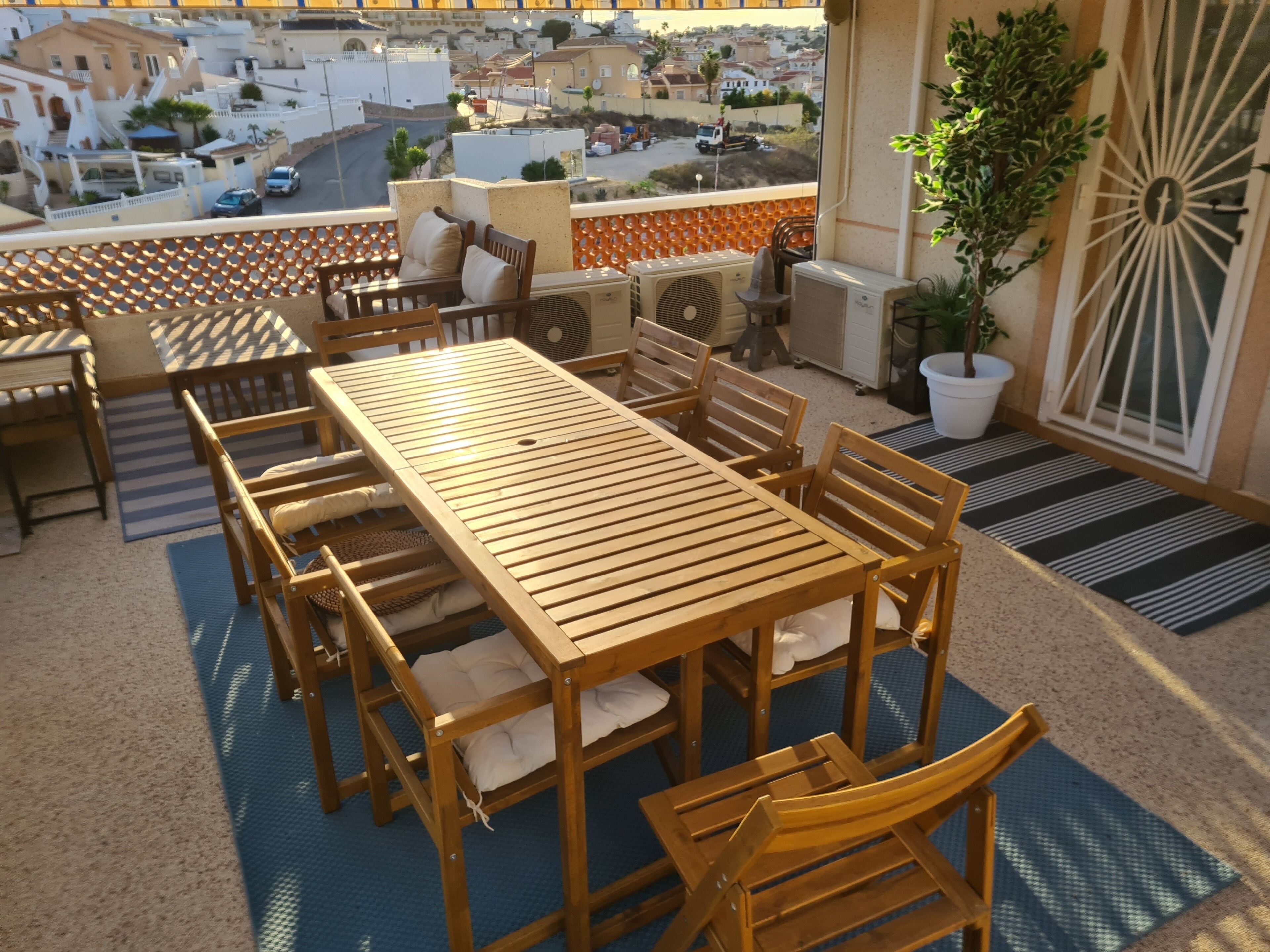A wooden table and chairs on a balcony with a city view.