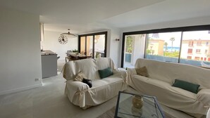 A modern living room with a sofa, a coffee table, and a dining area with a table and chairs. - Le Cosy Beach (Saint-Cyr-sur-Mer)