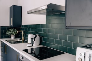 A modern kitchen with a built-in stove, a coffee maker, and a toaster. - Tranquility Parkside luxury 2 bed garden apartment (Worthing)