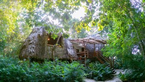 A thatched-roof structure with a wooden staircase leading to a platform. - Posada del Cerro (Flores)