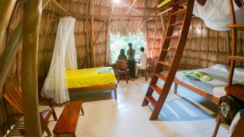 A rustic room with a thatched roof, wooden furniture, and a bed with a mosquito net.