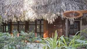 A rustic building with a thatched roof, wooden windows, and a wooden door. - Posada del Cerro (Flores)