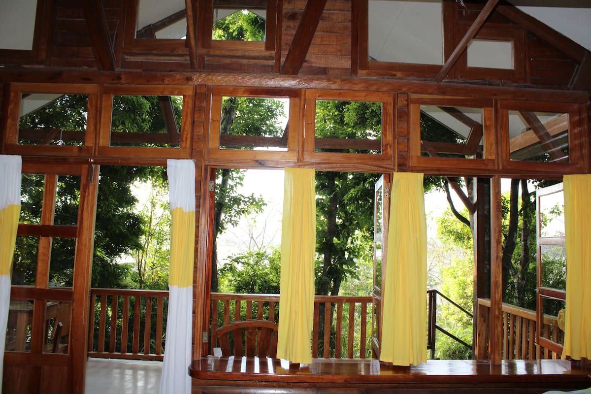 Escadaria de madeira com vista para árvores pelas janelas.