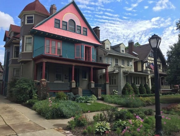 Une maison de style victorien, reconnaissable à son toit rouge vif, à ses nombreuses fenêtres et à son jardin bien entretenu.
