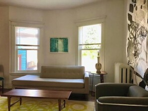 Un salon avec un canapé, une table basse et deux fenêtres.