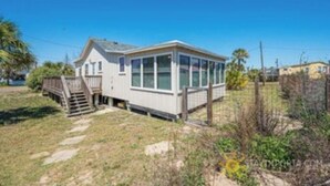 Ein eingeschossiges Haus mit überdachter Veranda und einer kleinen Treppe zum Eingang.