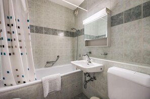 Un baño con bañera, lavamanos, inodoro y cortina de ducha.
