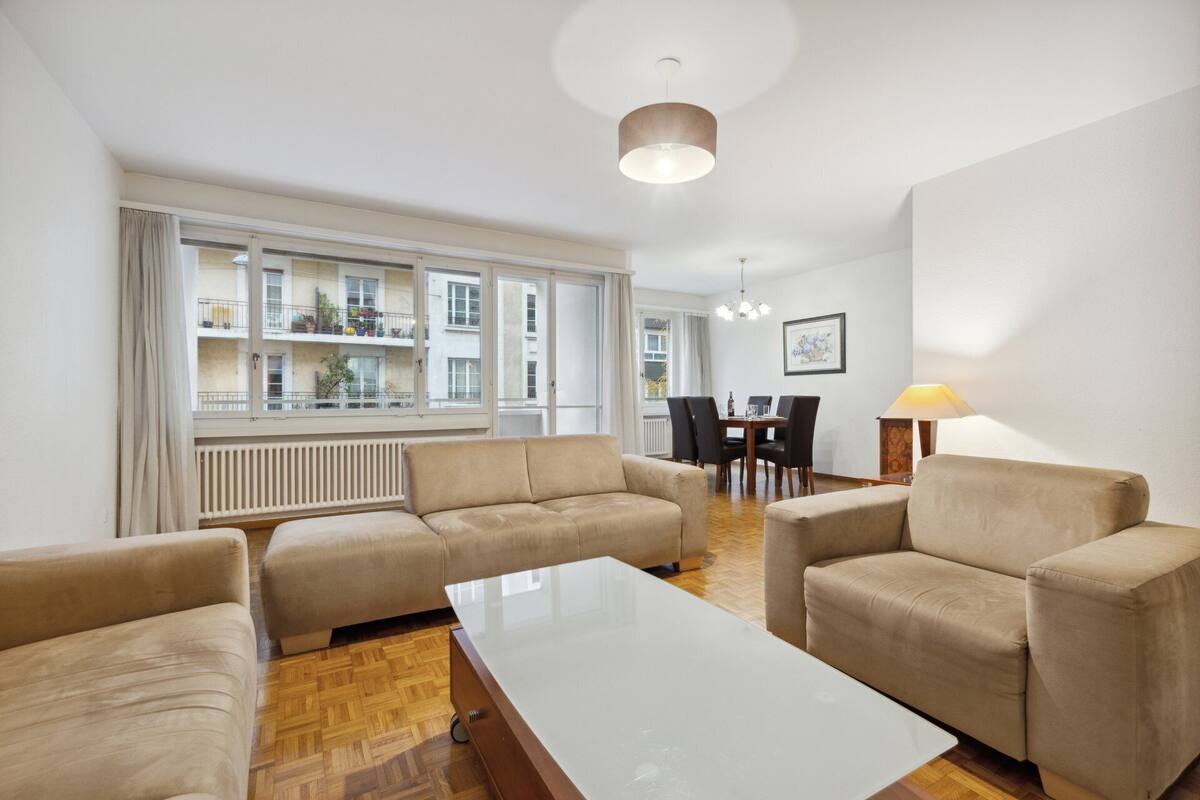 A modern living room with a sofa set, a coffee table, and a dining area with chairs and a table.