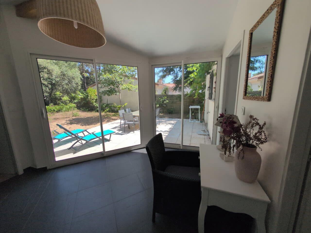 Quarto com uma grande porta de vidro deslizante que dá para um pátio externo com piscina e cadeiras.