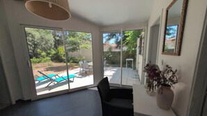 A room with a large sliding glass door leading to an outdoor patio with a pool and chairs.