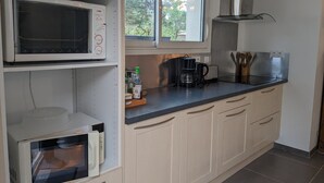 A modern kitchen with a microwave, coffee maker, and a window with a view of trees.
