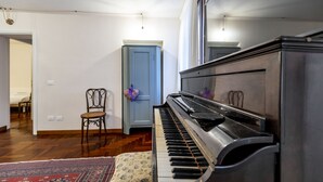 A room with a piano, a patterned rug, a chair, and a door. - SAN SILVESTRO HOUSE VENICE FIRST FLOOR (Venezia)