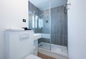Une salle de bain moderne avec une douche à parois de verre, un lavabo blanc et un porte-serviettes.