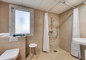 Ein Badezimmer mit Toilette, Waschbecken, einer Duschkabine und einem Fenster.