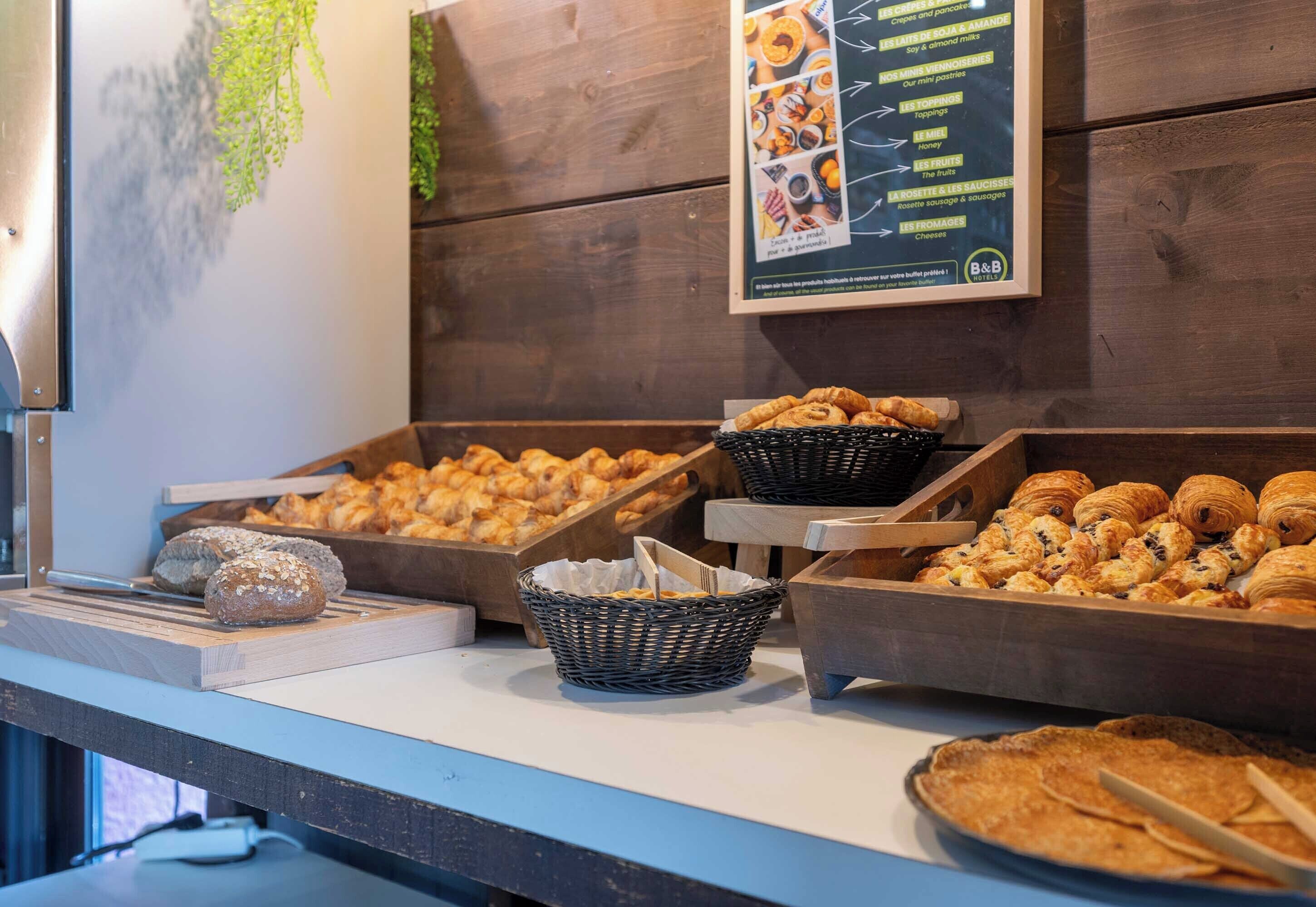 A breakfast buffet with various pastries and bread displayed in baskets and wooden trays.