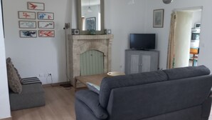 A living room with a fireplace, a sofa, a television, and a dining area.
