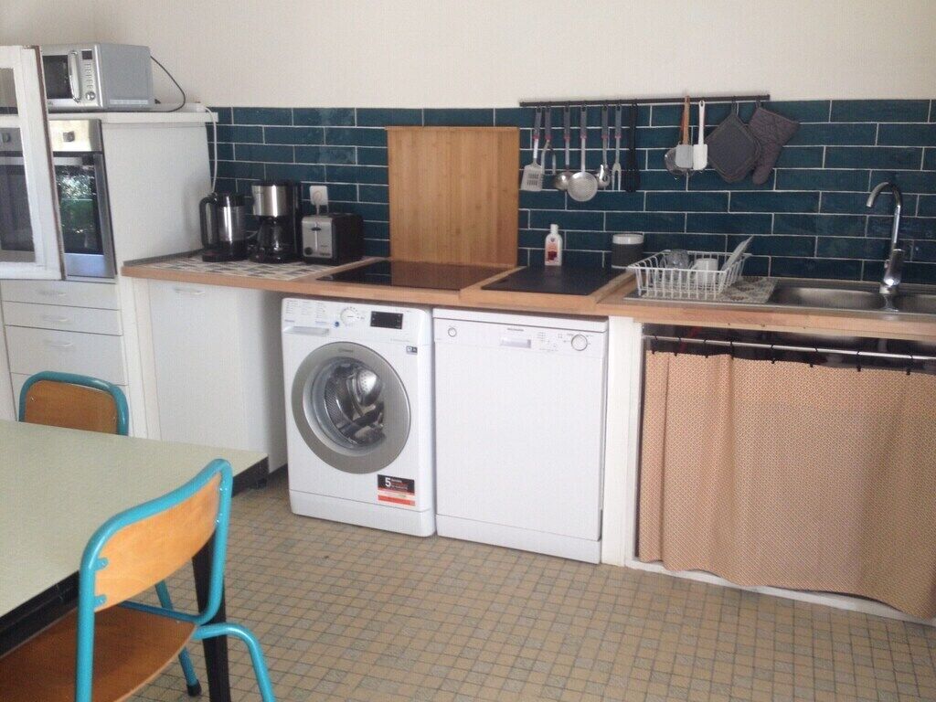 A compact kitchen with a washing machine, a microwave, and a sink.