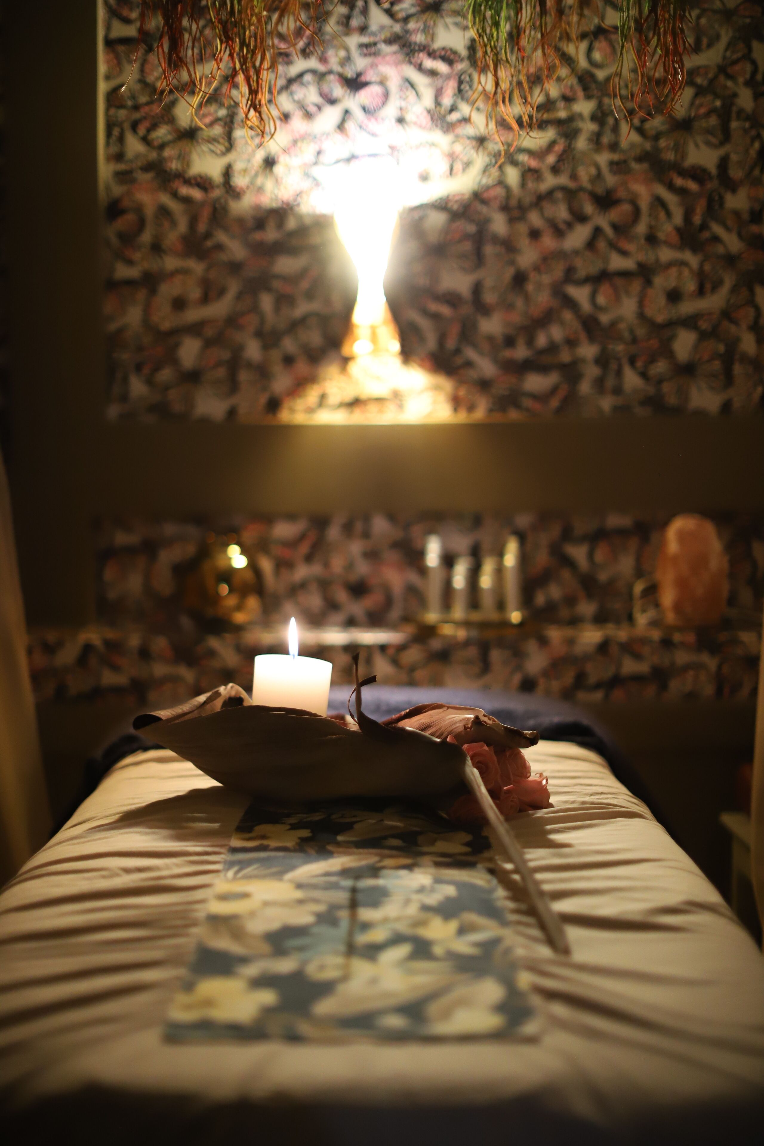 A room with a bed, a lit candle, and a patterned wall.
