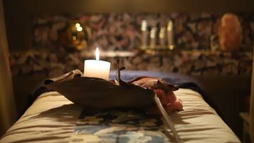 A room with a bed, a lit candle, and a patterned wall.