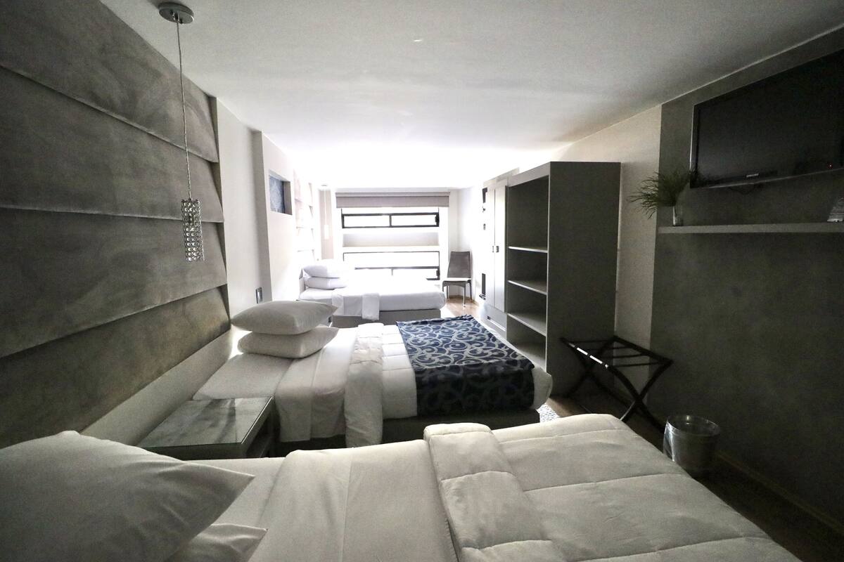 Una habitación de hotel moderna con una cama grande, una cama más pequeña, un televisor y un área de descanso.