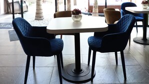 Ein moderner Essbereich mit einem runden Tisch, blauen Polsterstühlen und hängenden Leuchten.