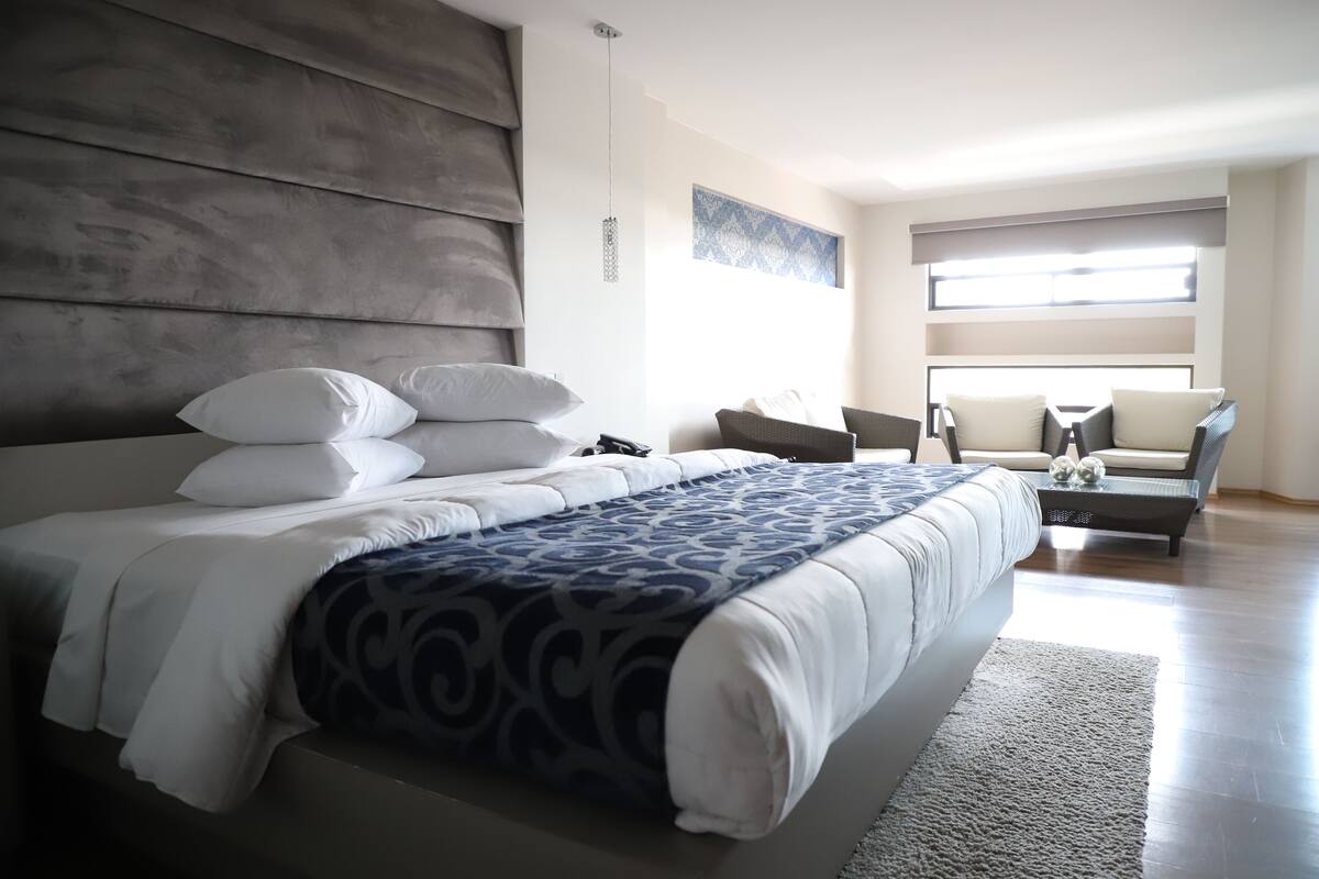 Un dormitorio moderno con una cama grande, un sofá y una zona de comedor.