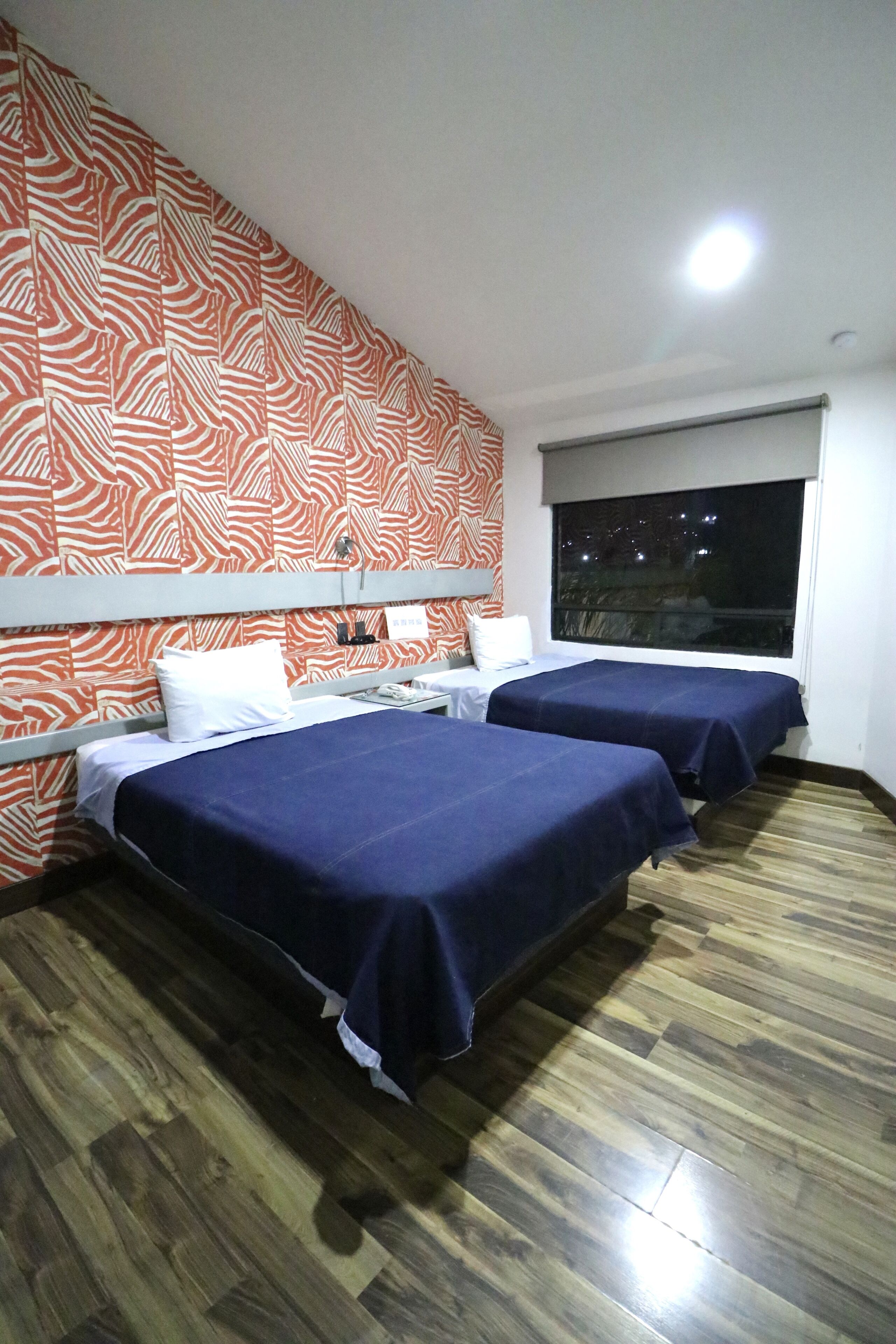 Een hotelkamer met twee bedden, een groot raam en een muur met een zebrapatroon.