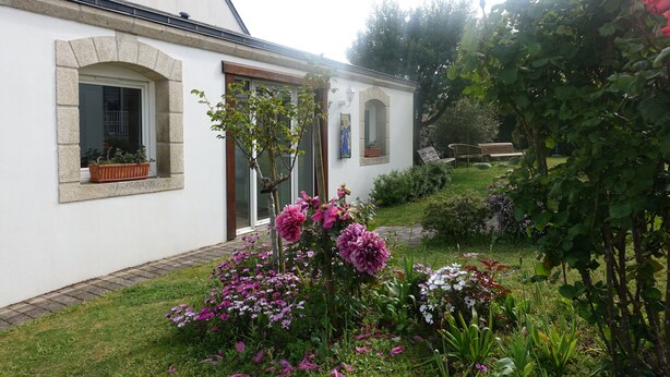 Un bâtiment blanc avec un arc en pierre, une porte et une fenêtre ornée d’un pot de fleurs.