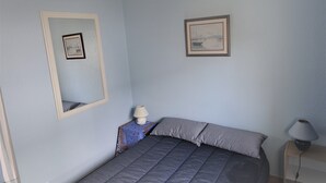 Une chambre à coucher avec un lit, deux lampes de chevet et deux tableaux encadrés accrochés au mur.