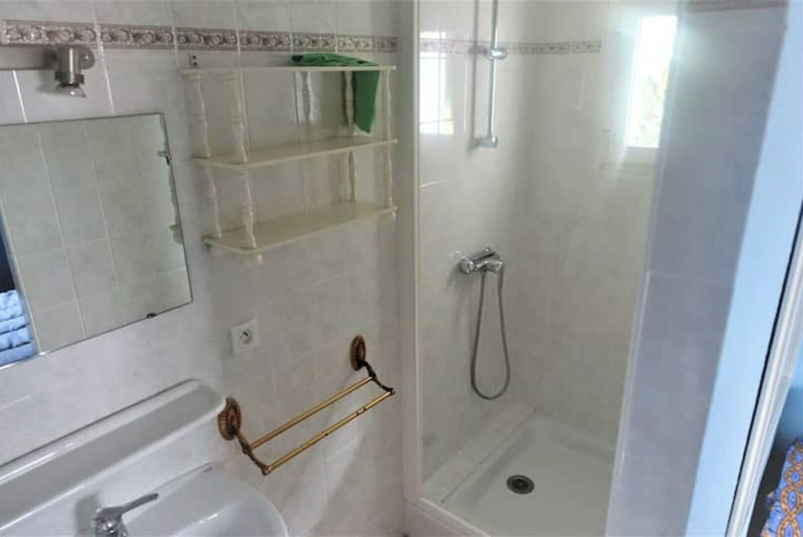 A bathroom with a sink, mirror, and a shower enclosure.
