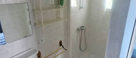 A bathroom with a sink, mirror, and a shower enclosure.