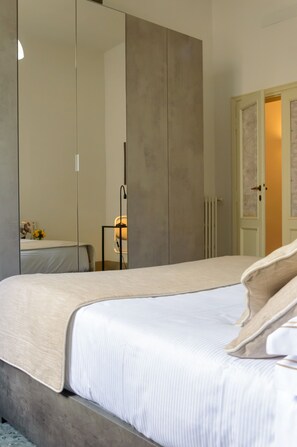 A bedroom with a large bed, a wardrobe, a bedside table, and a lamp. - Homelink Firenze -  Charlotte  (Florence)