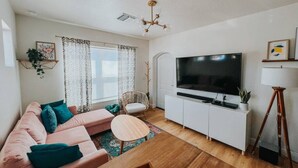 Una sala de estar moderna con un sofá, una mesa de centro, un televisor y una lámpara.