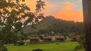 A rustic cabin area with multiple wooden cabins, a grassy lawn, and a small pond. - Riverside Suite Casita 6 (Greer)
