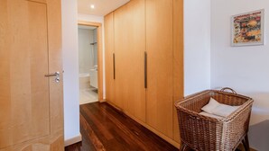 A hallway with wooden wardrobes, a wicker basket, and a poster on the wall. - D. João IV Apartment w/ Terrace by LovelyStay (Porto)