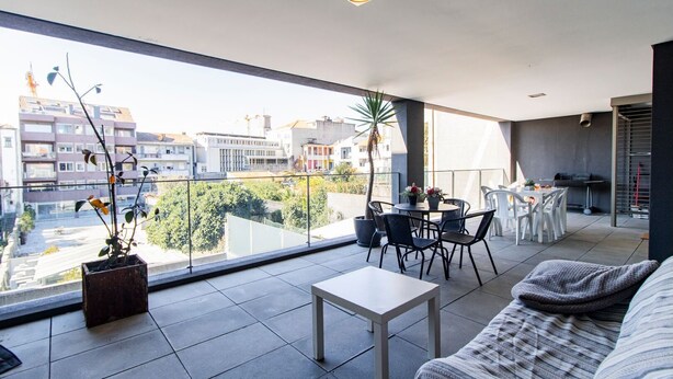 A modern apartment with a balcony, a dining area, and a sofa. - D. João IV Apartment w/ Terrace by LovelyStay (Porto)