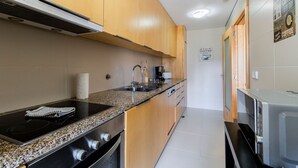 A modern kitchen with wooden cabinets, a built-in stove, a coffee machine, and a microwave. - D. João IV Apartment w/ Terrace by LovelyStay (Porto)