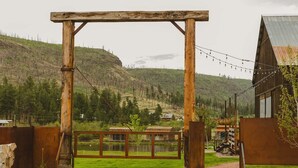 Un arco de madera rústico que da paso a un área cercada con vistas a un paisaje montañoso.