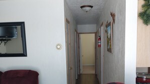 Un pasillo con una butaca roja, un sillón color beige y piso de madera.