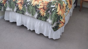 Una cama con una colcha estampada con flores y un cuadro de girasoles en la pared.