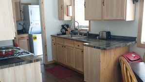 Una cocina compacta con armarios de madera, estufa integrada y un lavamanos.