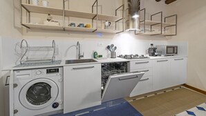 A compact kitchen with a built-in washing machine, a dishwasher, and a microwave. - SAN SILVESTRO HOUSE VENICE (Venezia)